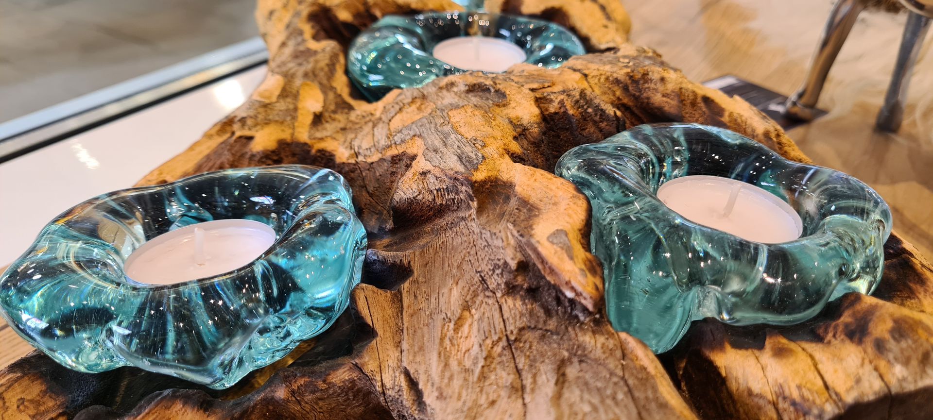 Auf einem Stück Holz stehen drei Kerzen.