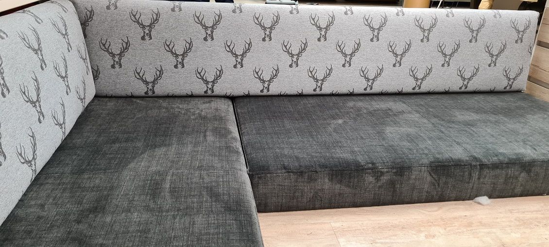 Auf einem gefliesten Boden steht ein graues Sofa mit einem Hirschmuster.