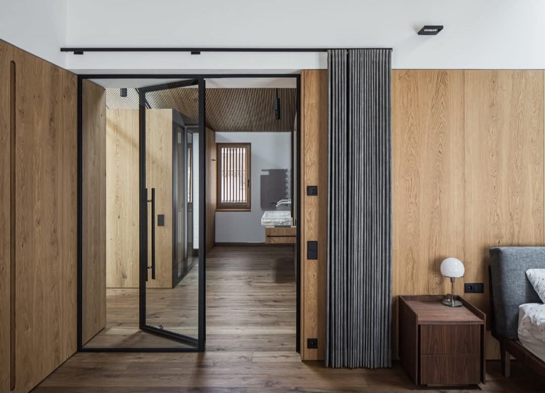 Ein Schlafzimmer mit einer Glasschiebetür, die zu einem Badezimmer führt.