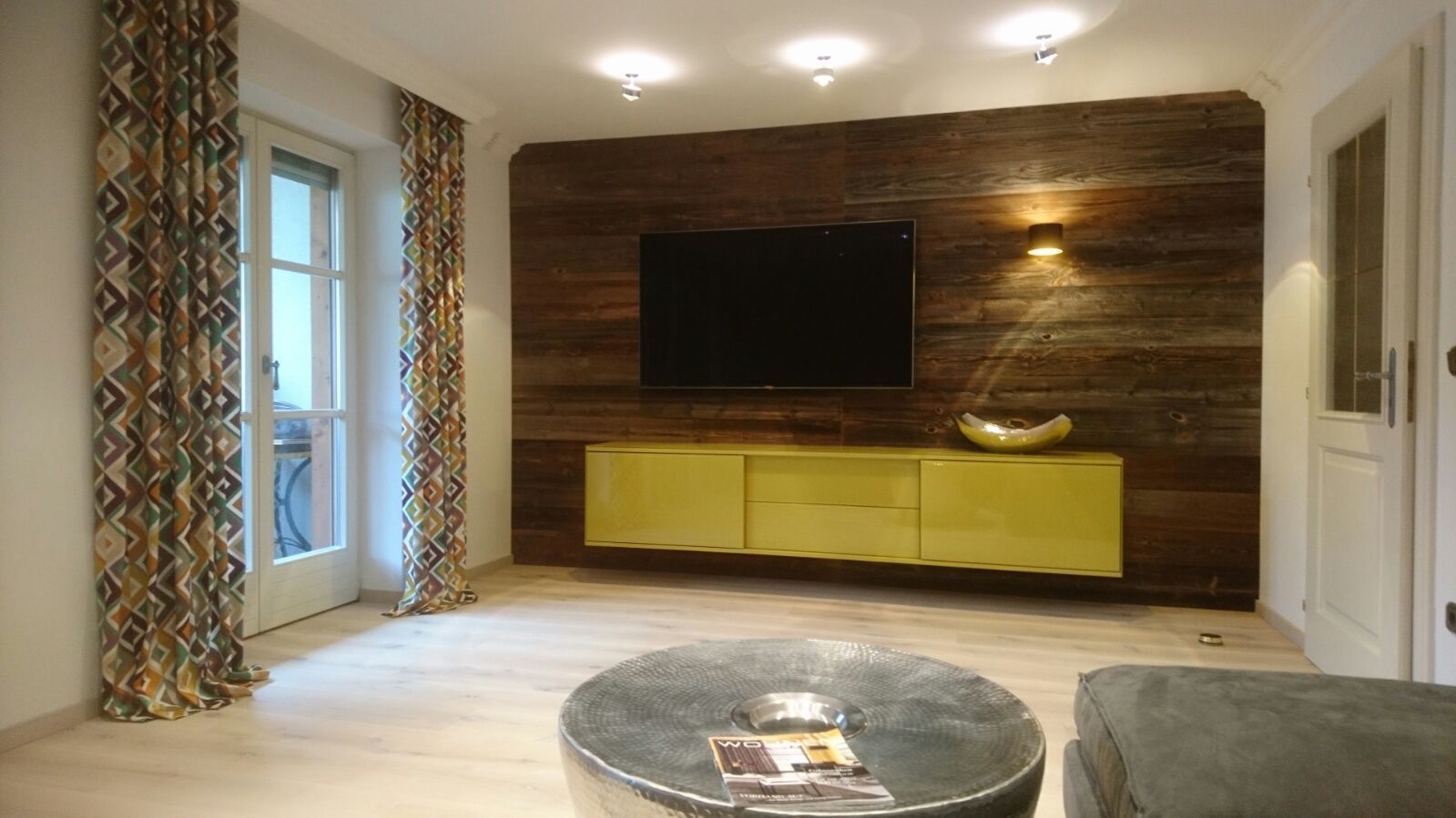 Ein Wohnzimmer mit einem Flachbildfernseher an der Wand.