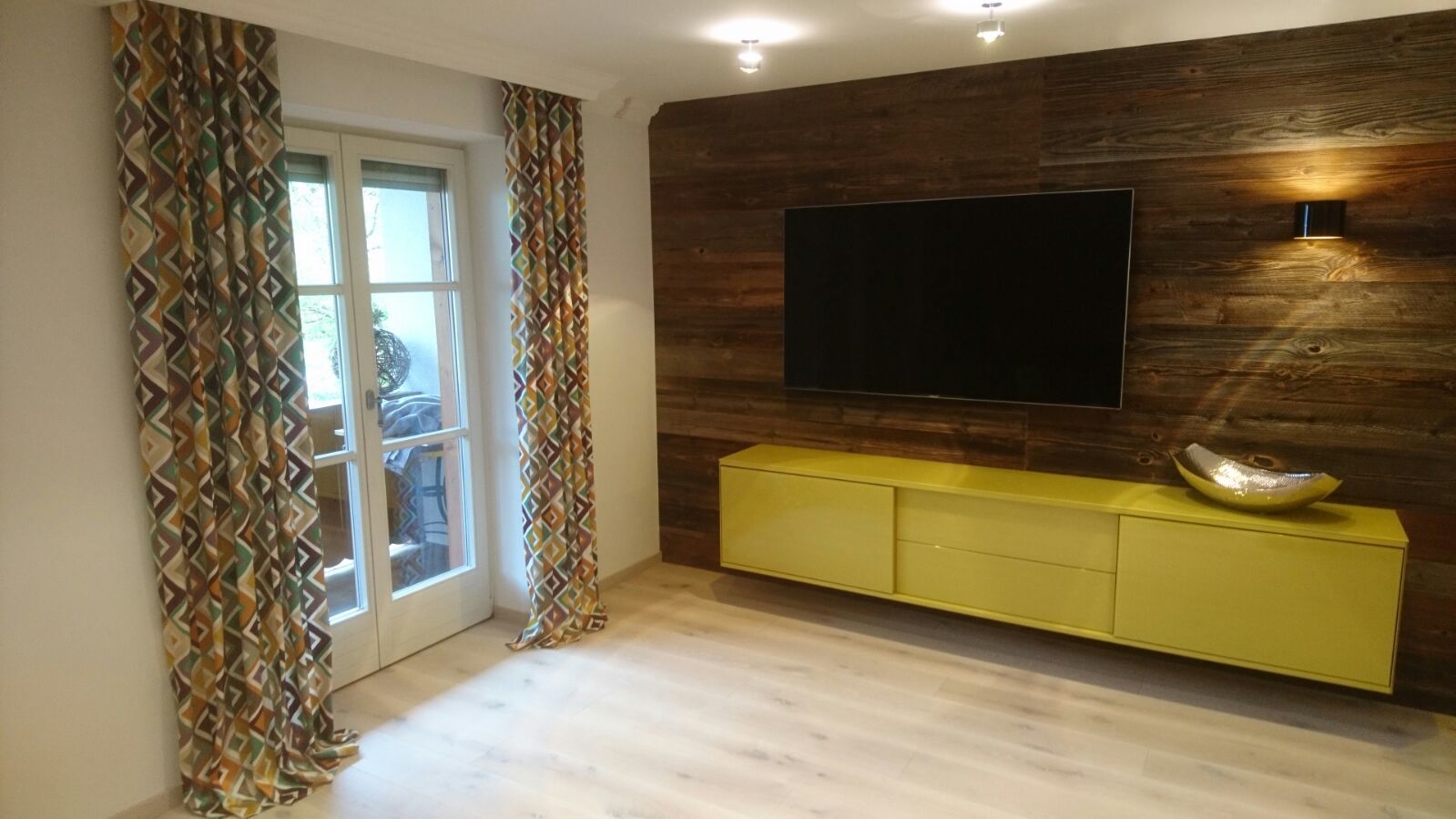 Ein Wohnzimmer mit einem großen Flachbildfernseher an der Wand.