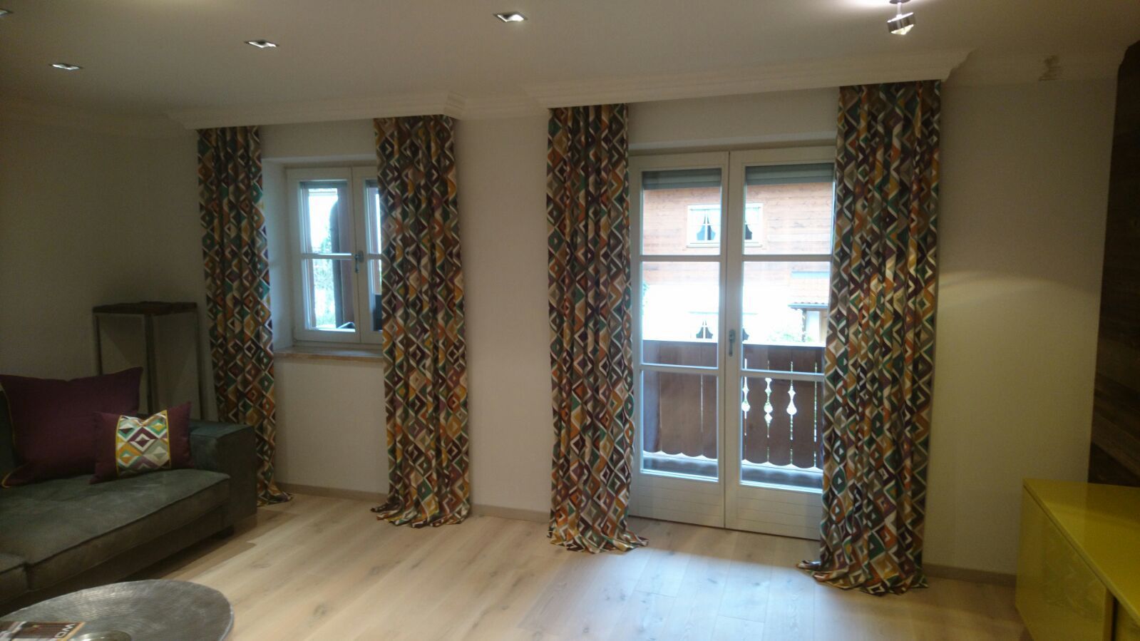 Ein Wohnzimmer mit Couch, Vorhängen und Glasschiebetür.