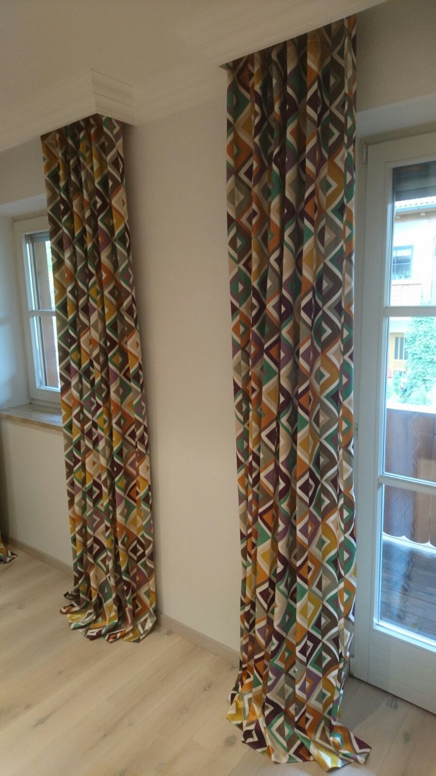 Ein Paar bunte Vorhänge hängen an einem Fenster in einem Wohnzimmer.