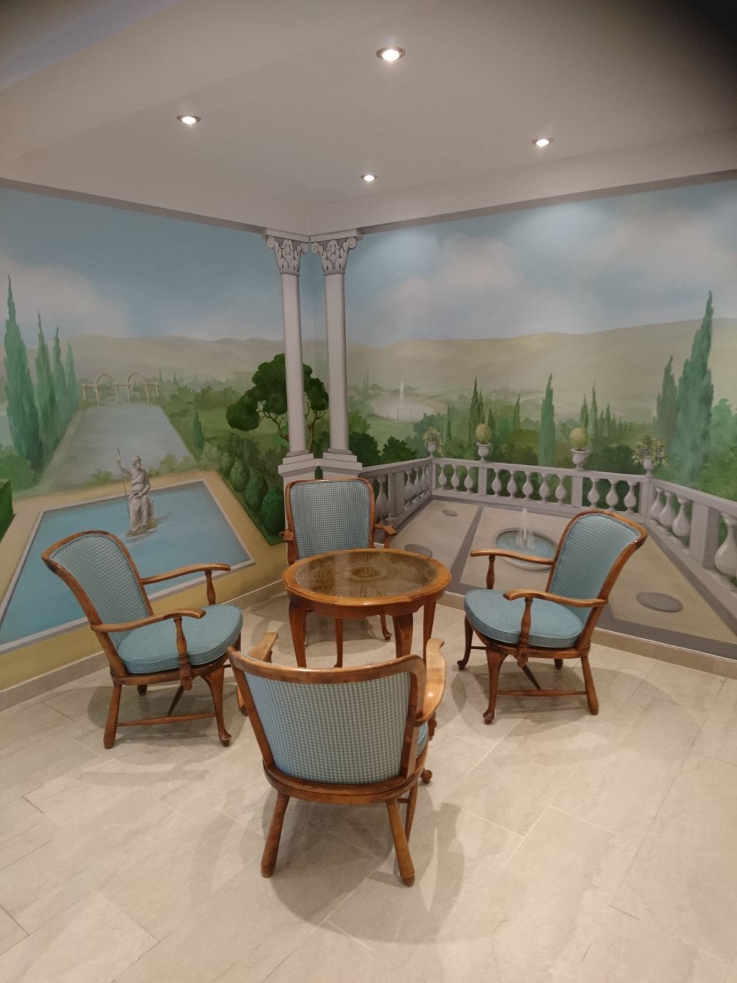 Ein Raum mit Stühlen und einem Tisch und einem Gemälde an der Wand.