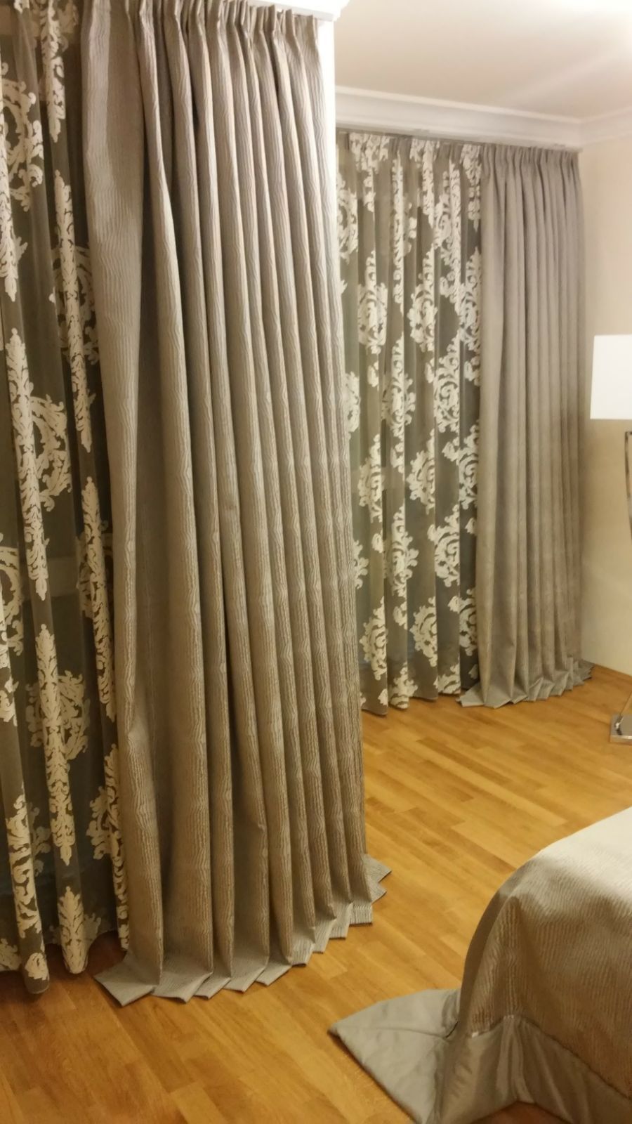 Ein Schlafzimmer mit einem Bett, Vorhängen und einer Lampe.