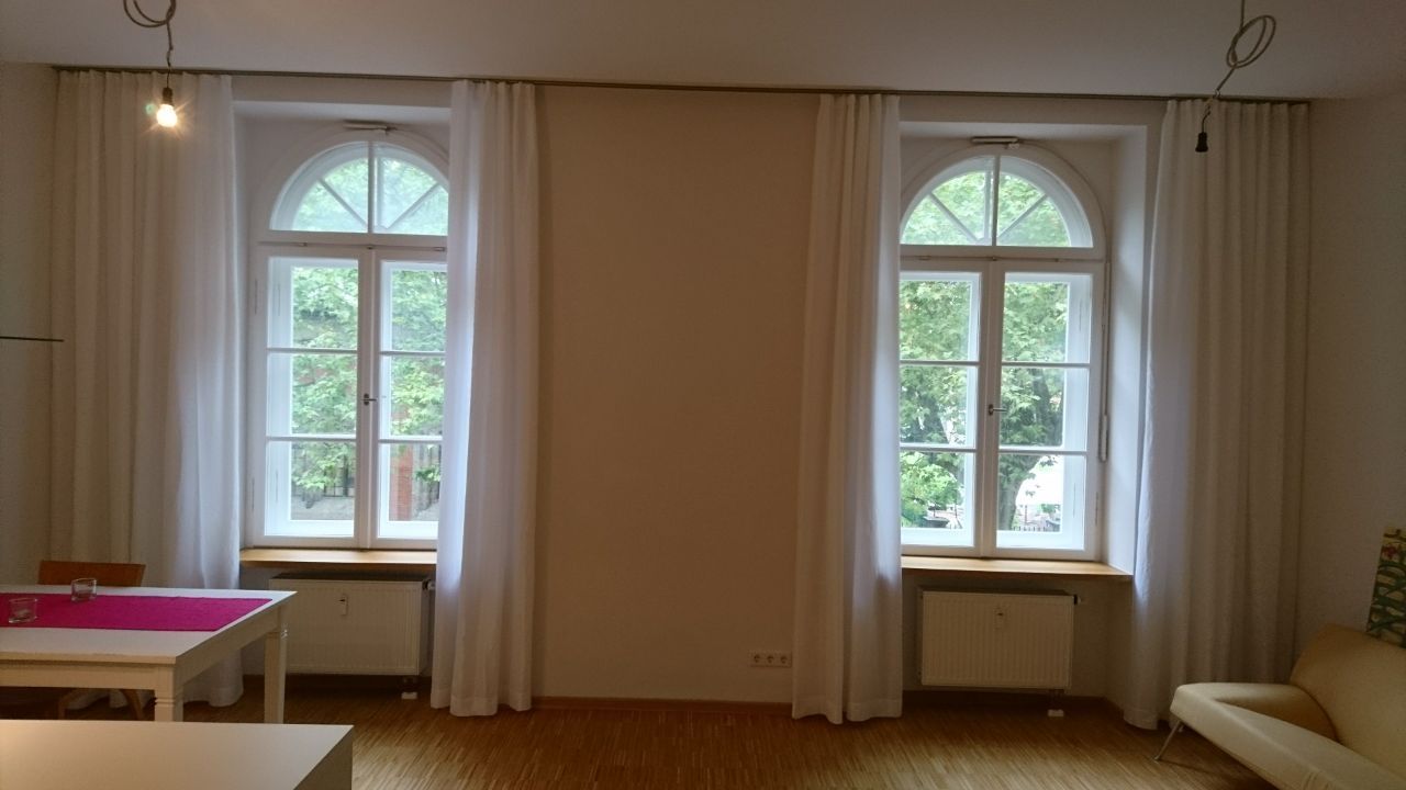 Ein Wohnzimmer mit weißen Vorhängen und zwei Fenstern