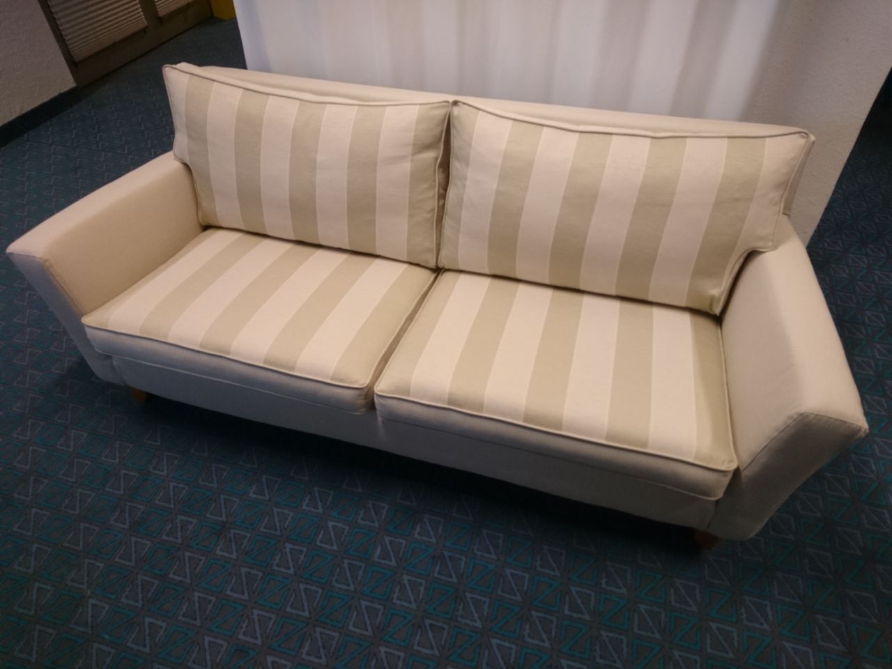 Eine weiß gestreifte Couch steht auf einem blauen Teppich