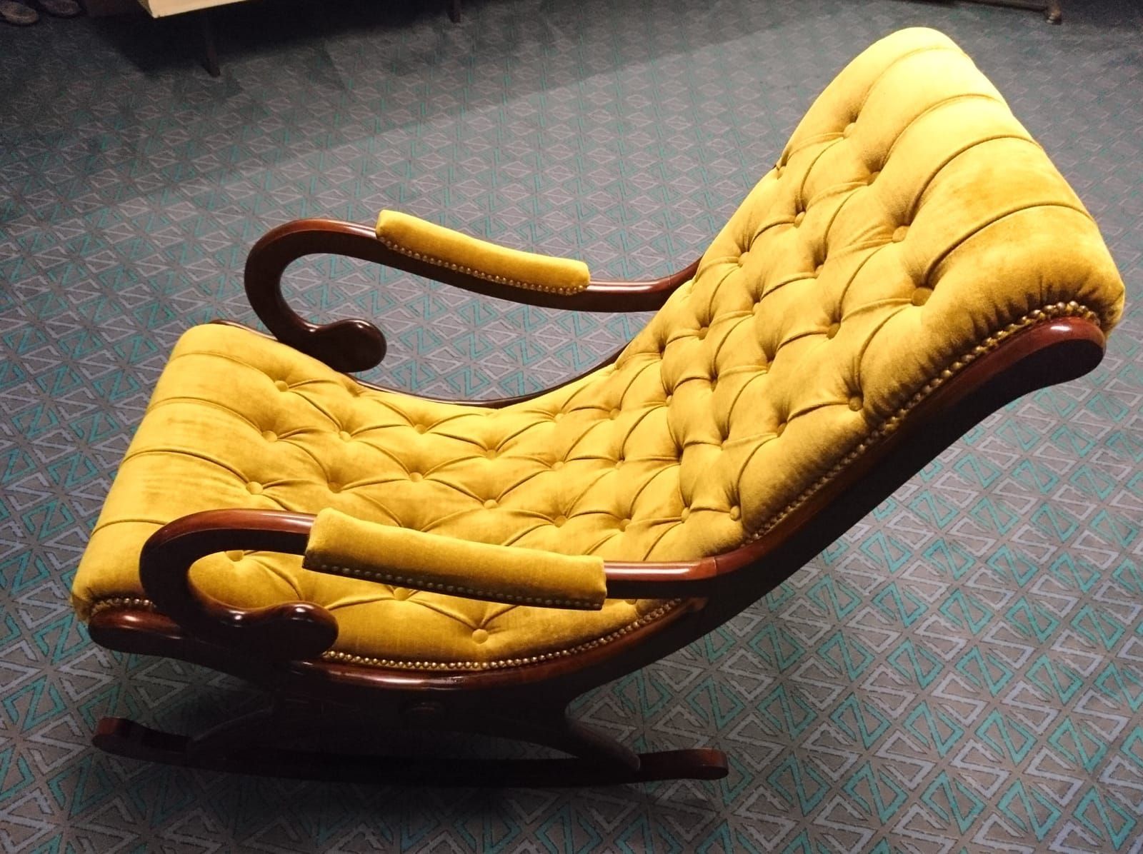 Ein gelber Schaukelstuhl steht auf einem grünen Teppich