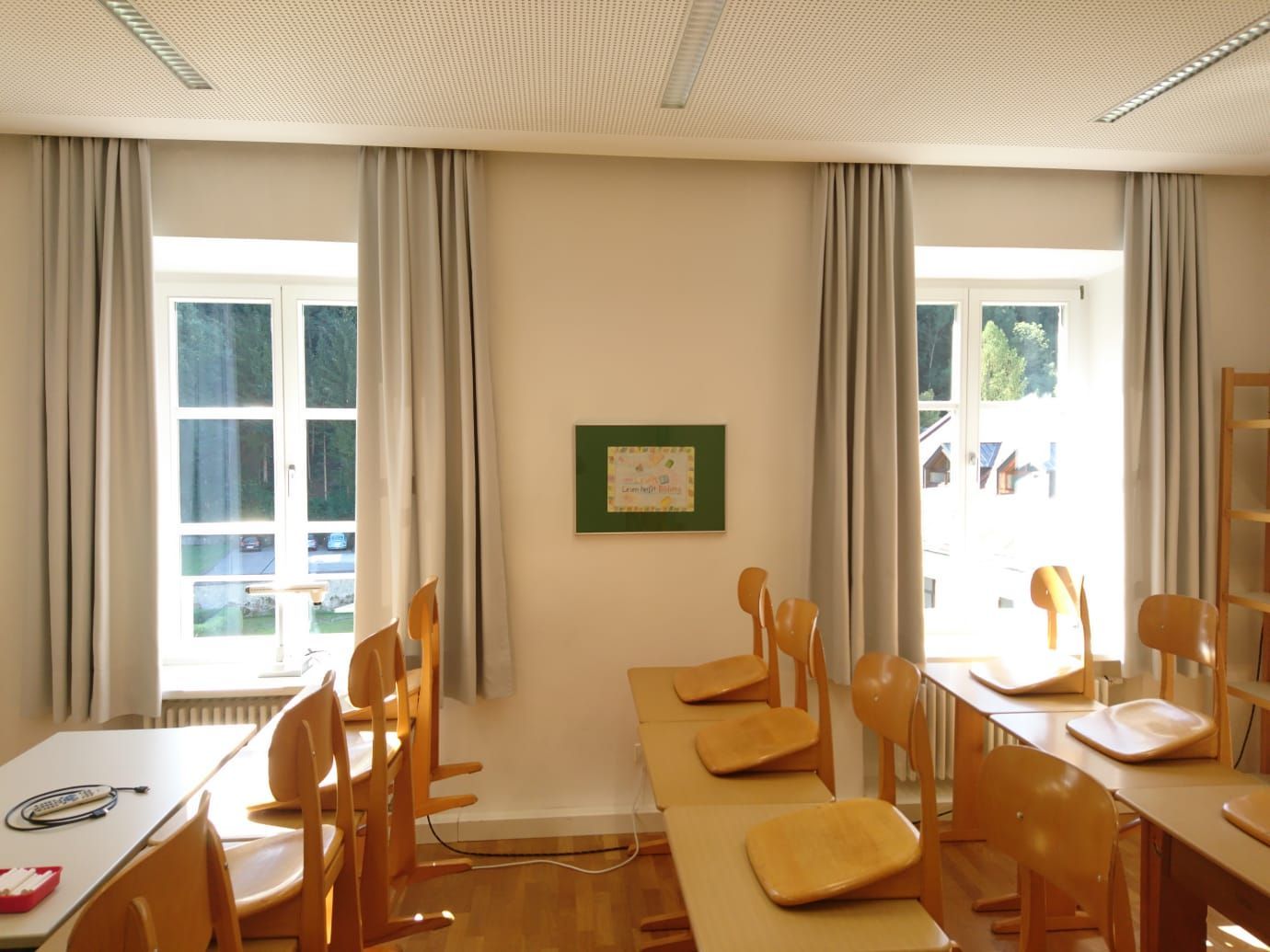 Ein Klassenzimmer mit Tischen und Stühlen und einem Bild an der Wand