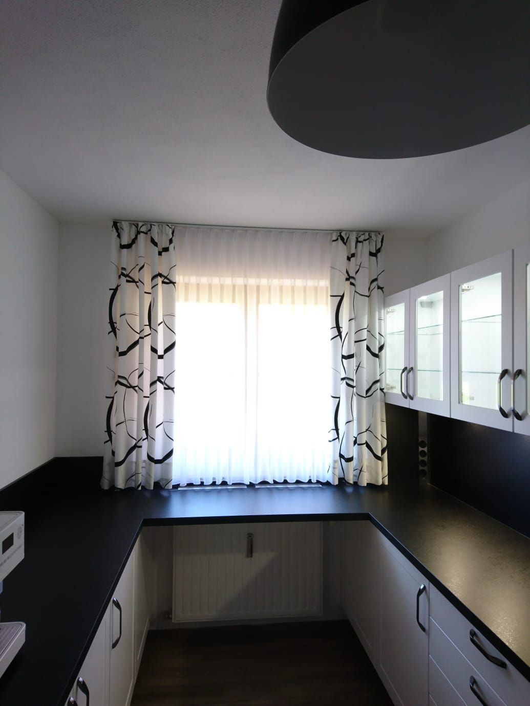 Eine Küche mit weißen Schränken und schwarzen Arbeitsplatten