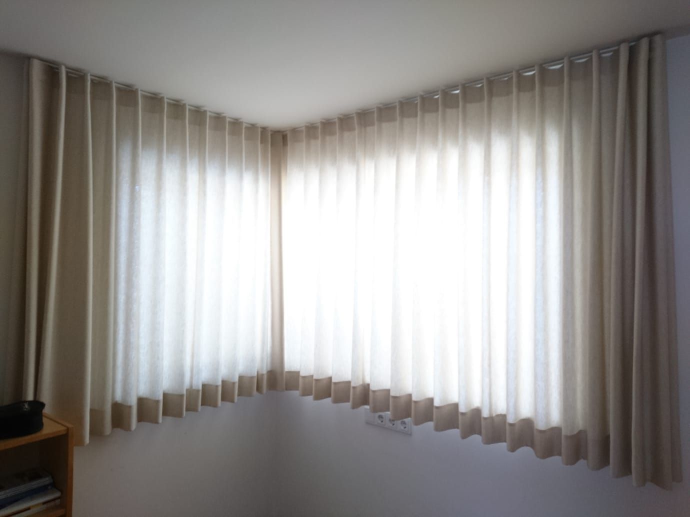 Ein Fenster mit weißen Vorhängen in einer Zimmerecke