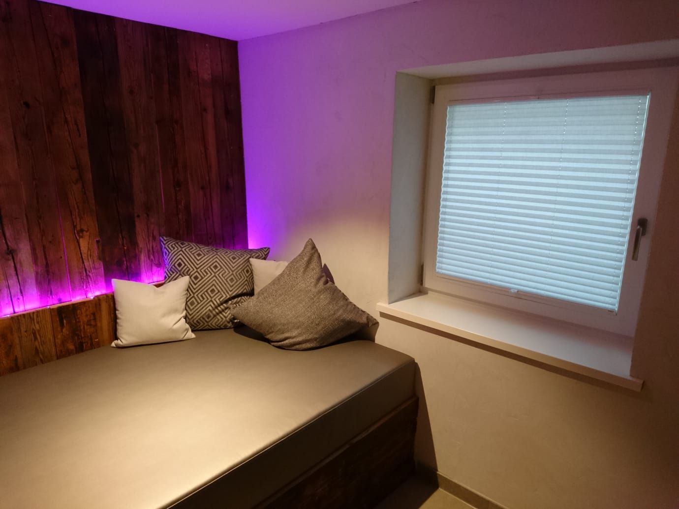 Ein Schlafzimmer mit einem Bett und einem Fenster mit violetten Lichtern.