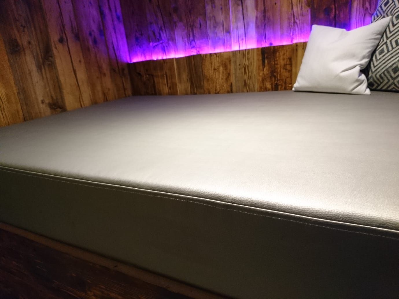 Eine Couch mit einem Kissen darauf in einem Raum mit Holzwänden.