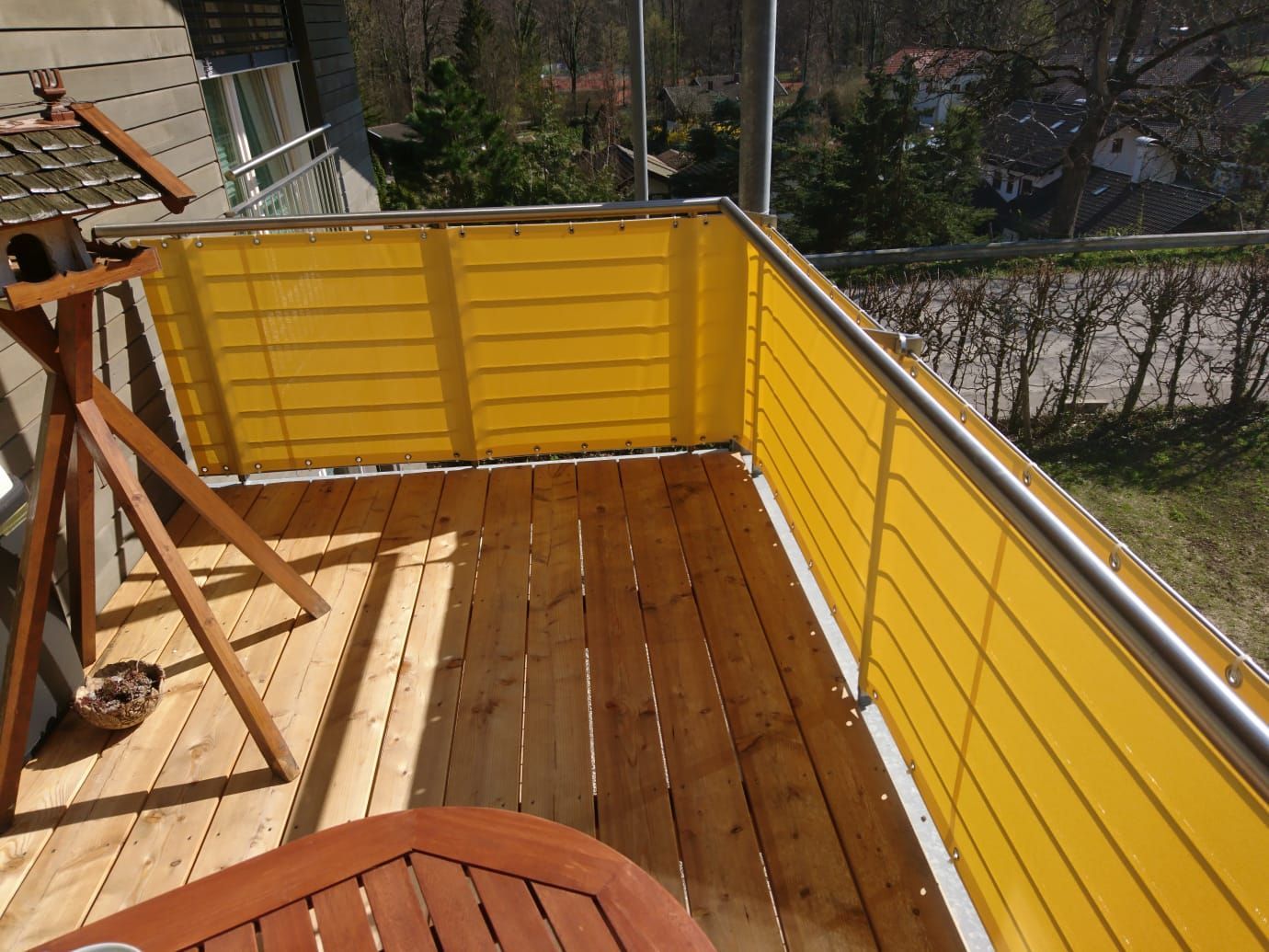 Ein Balkon mit einem gelben Zaun und einem Holztisch