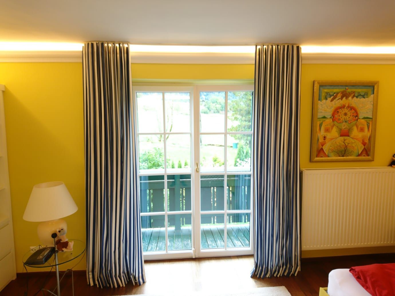 Ein Schlafzimmer mit gelben Wänden und gestreiften Vorhängen