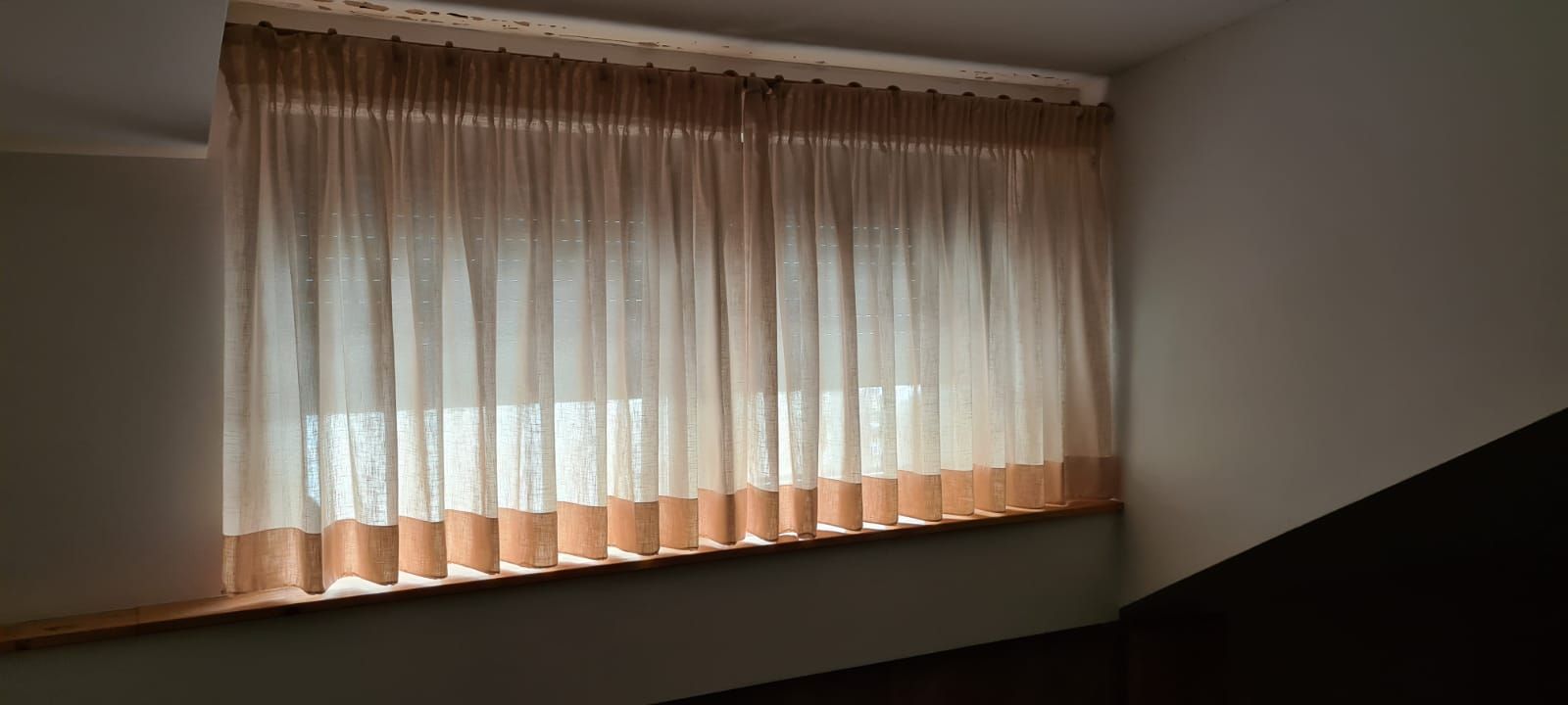 Ein Schlafzimmer mit einem großen Fenster und Vorhängen.