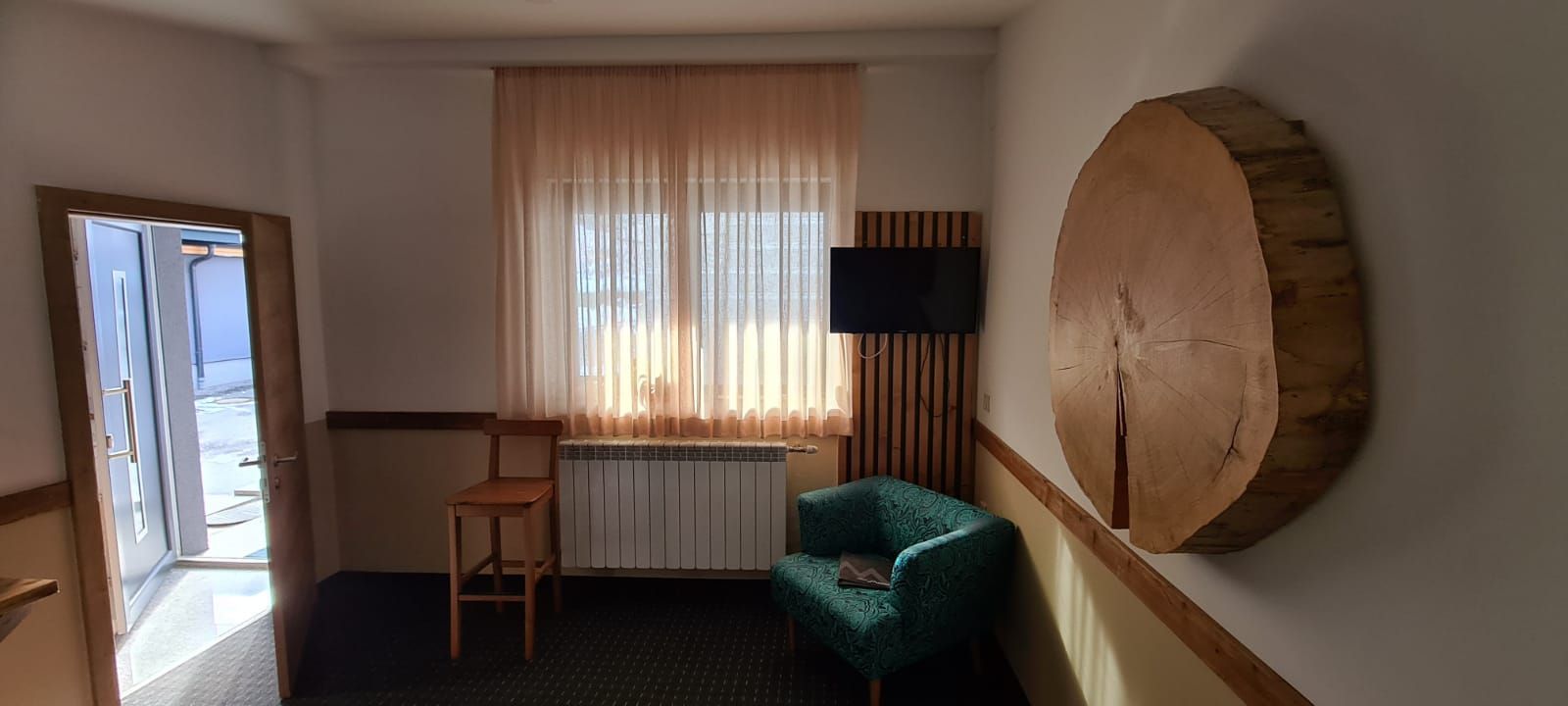 Ein Raum mit einem grünen Stuhl und einem Holzkreis an der Wand
