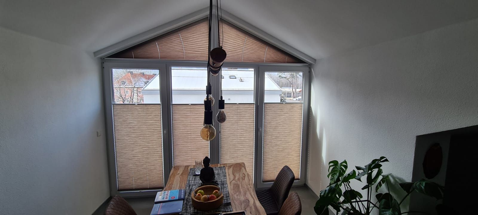 Ein Esszimmer mit Tisch und Stühlen vor einem großen Fenster.