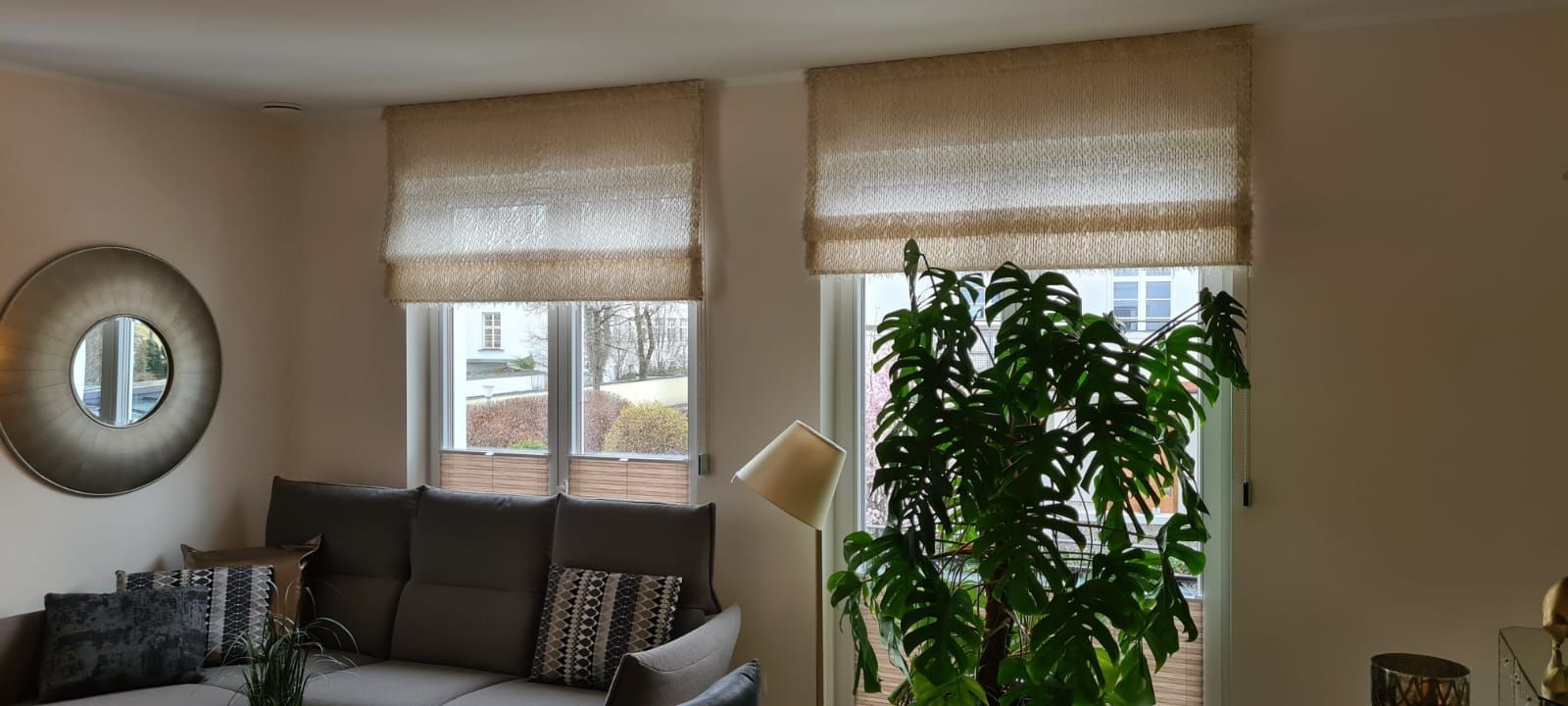 Ein Wohnzimmer mit Sofa, Lampe, Spiegel und Pflanze.