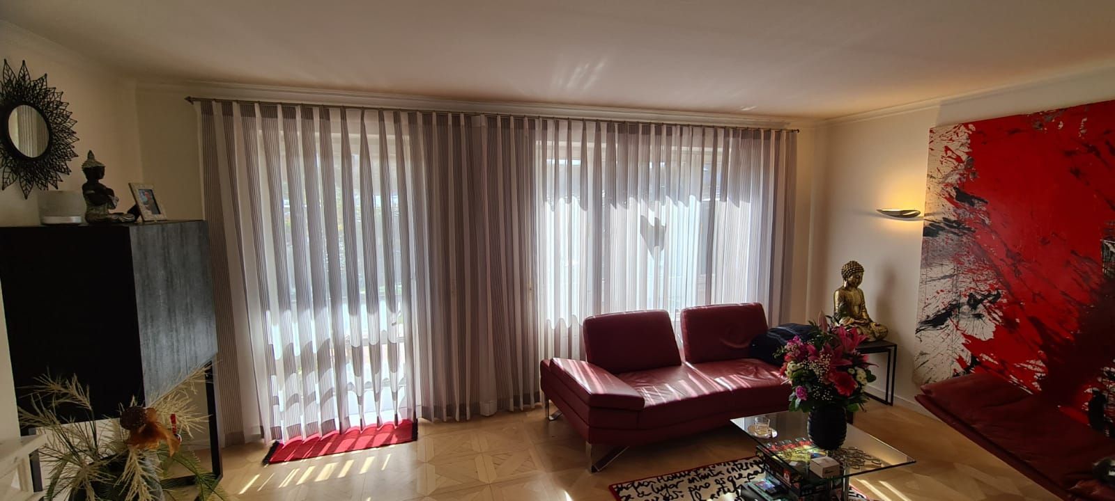 Ein Wohnzimmer mit einem roten Sofa und einem roten Gemälde an der Wand.