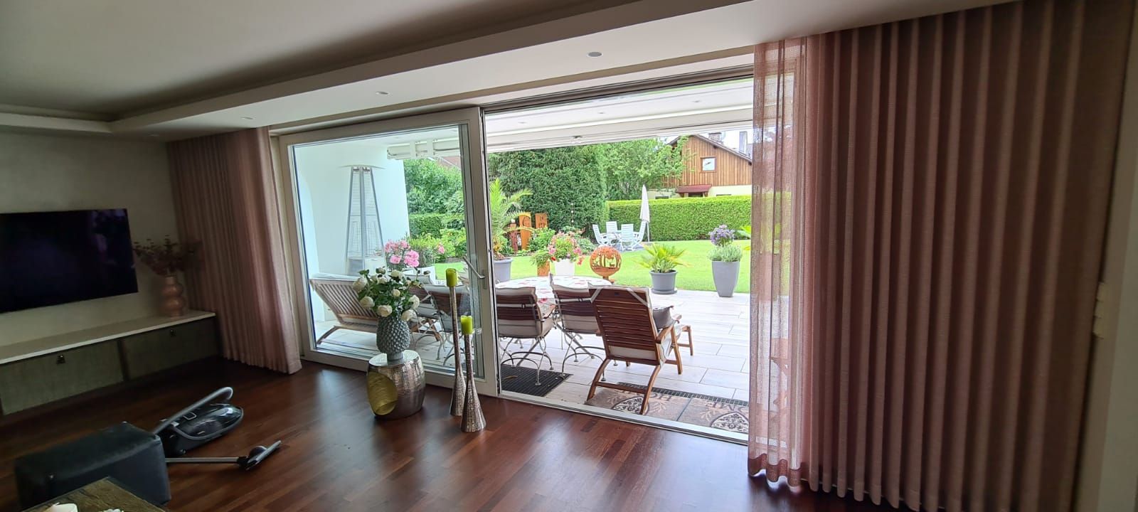 Ein Wohnzimmer mit einer Glasschiebetür, die auf eine Terrasse führt.