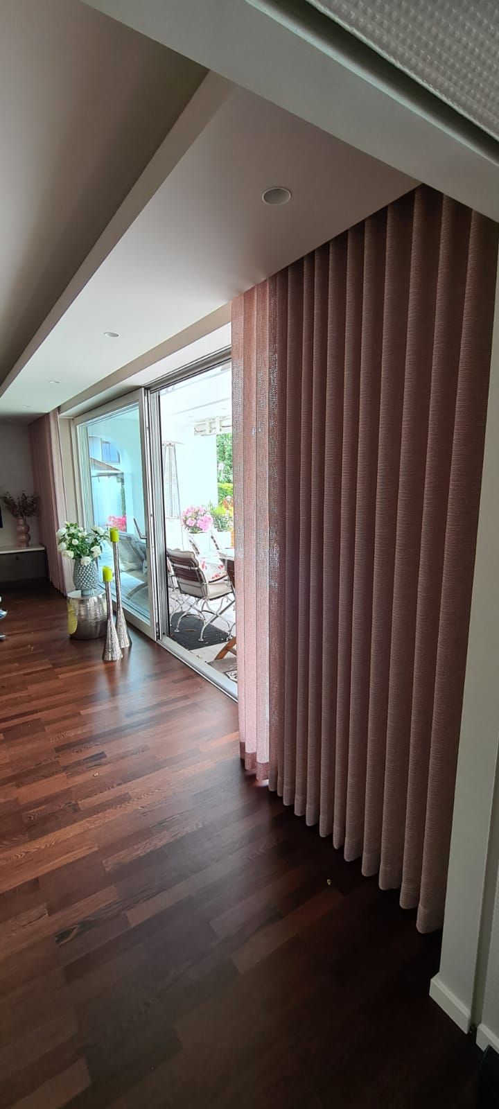 Ein Wohnzimmer mit einer Glasschiebetür und rosa Vorhängen.