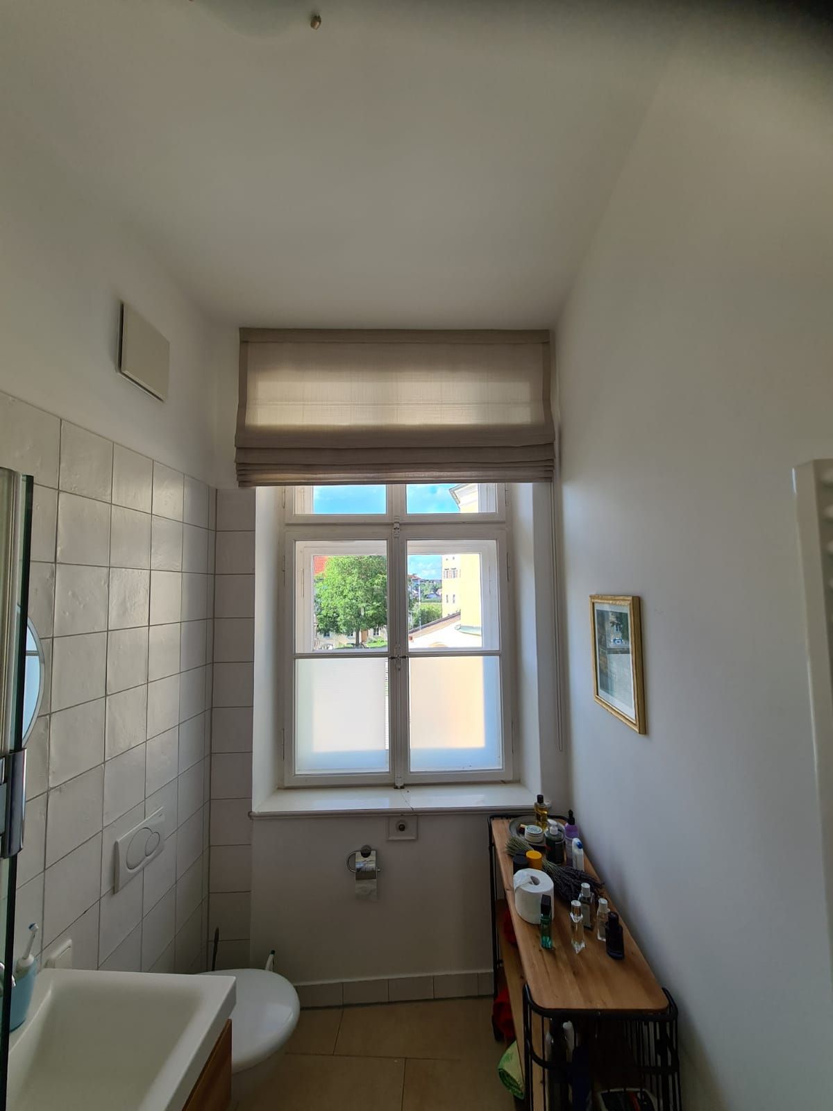 Ein Badezimmer mit Toilette, Waschbecken, Spiegel und Fenster.