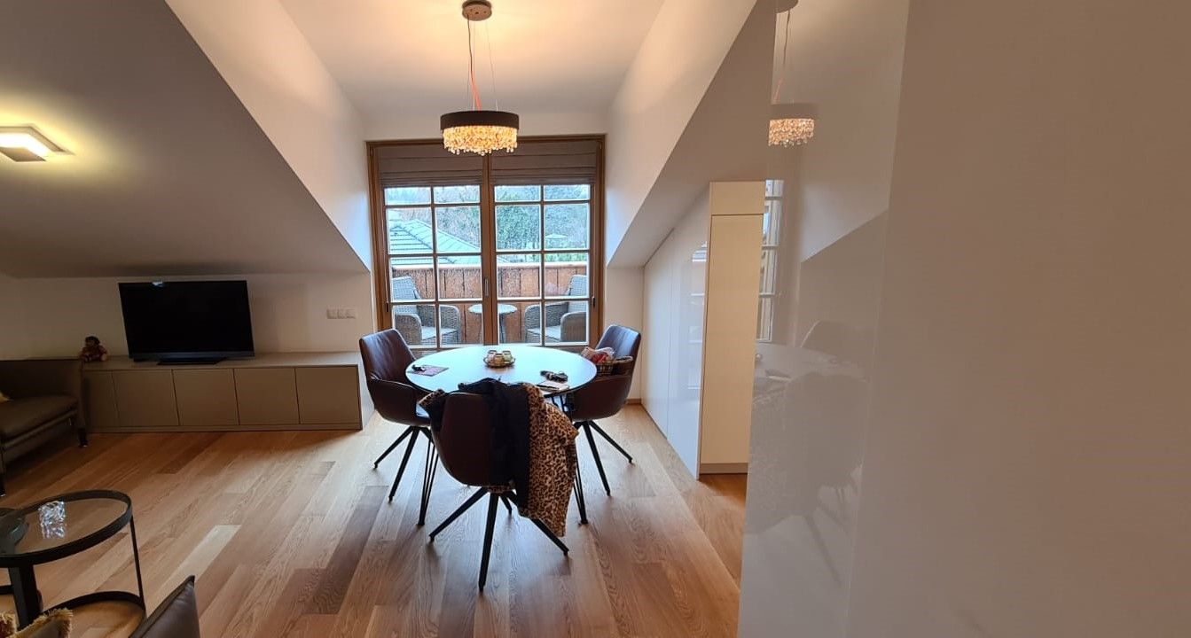 Ein Esszimmer mit einem runden Tisch und Stühlen und einem Flachbildfernseher.