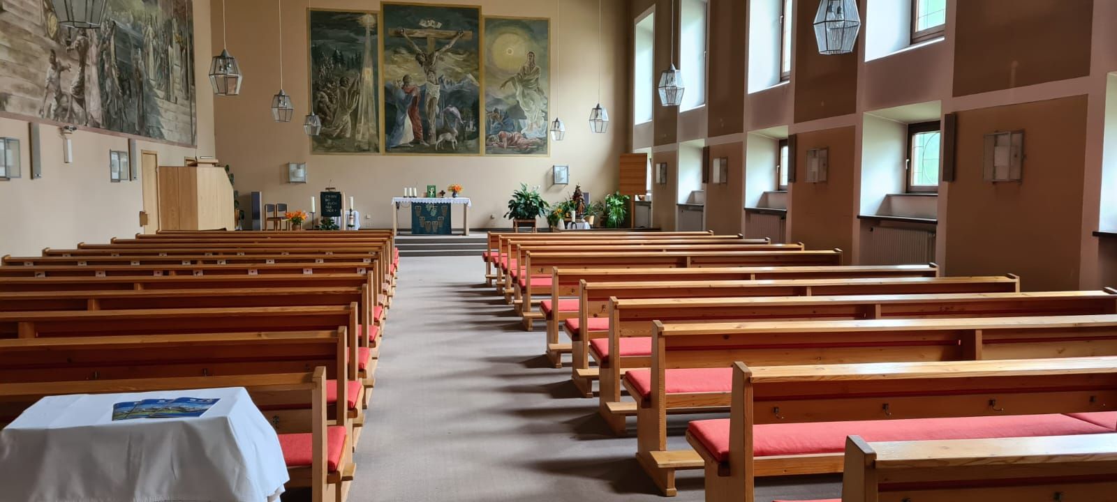 Eine Kirche mit Reihen von Holzbänken und einem Tisch in der Mitte.