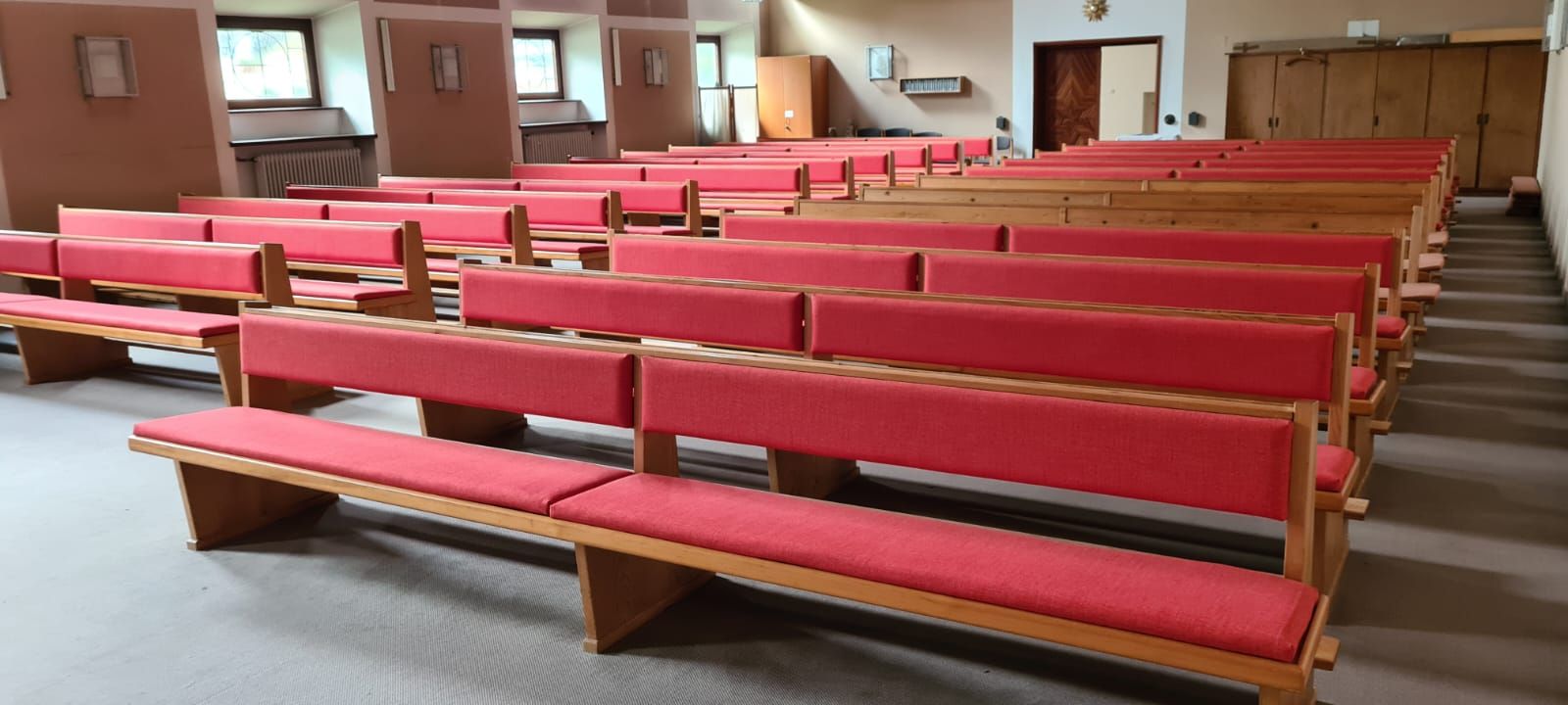 Eine Reihe roter Bänke in einer Kirche.