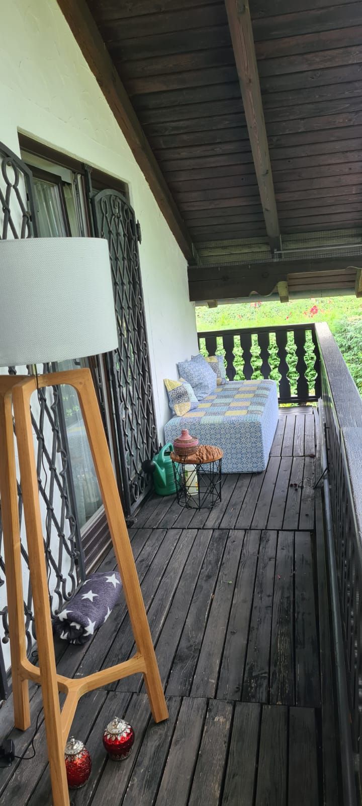 Eine Holzveranda mit einer Lampe und einem Sofa darauf.