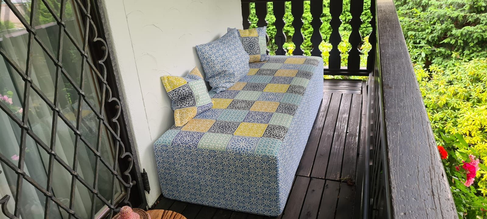 Auf einem Balkon steht neben einem Fenster ein Sofa.
