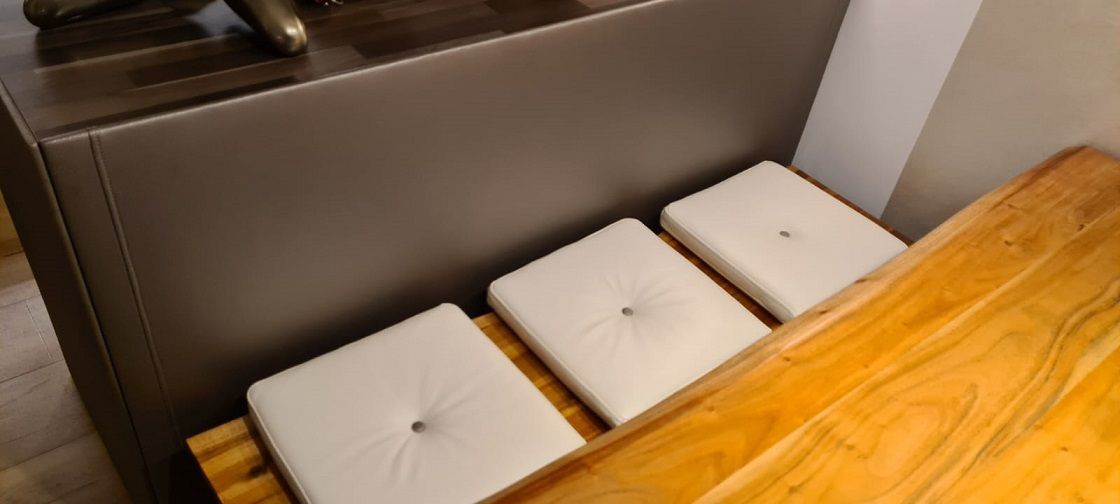 Auf einem Holztisch liegen drei weiße quadratische Kissen.