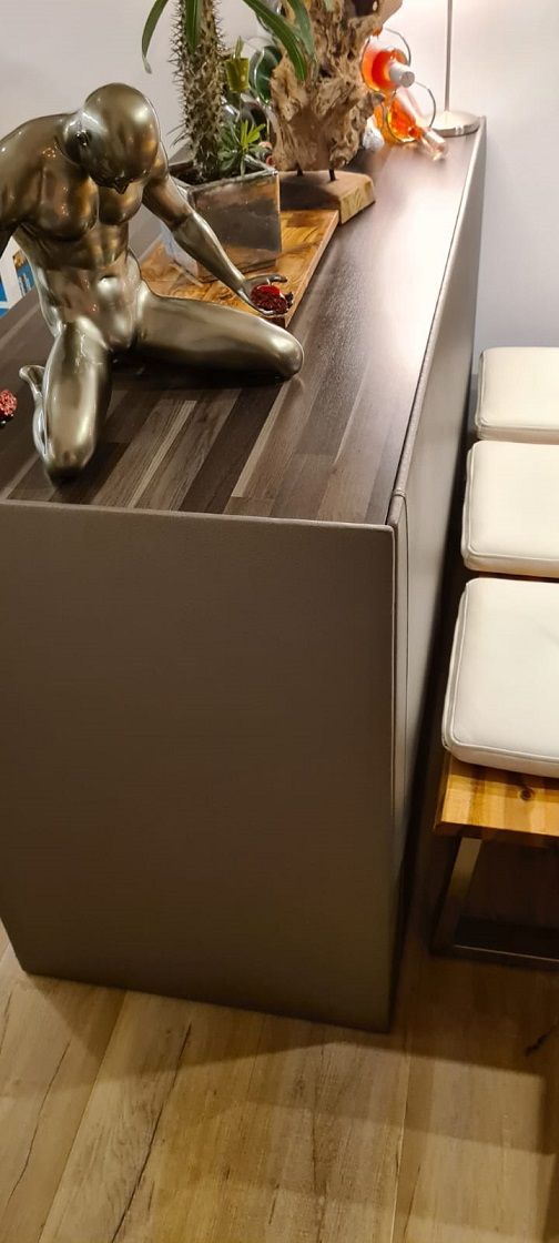 Auf einem Holztisch sitzt die Statue eines Mannes.