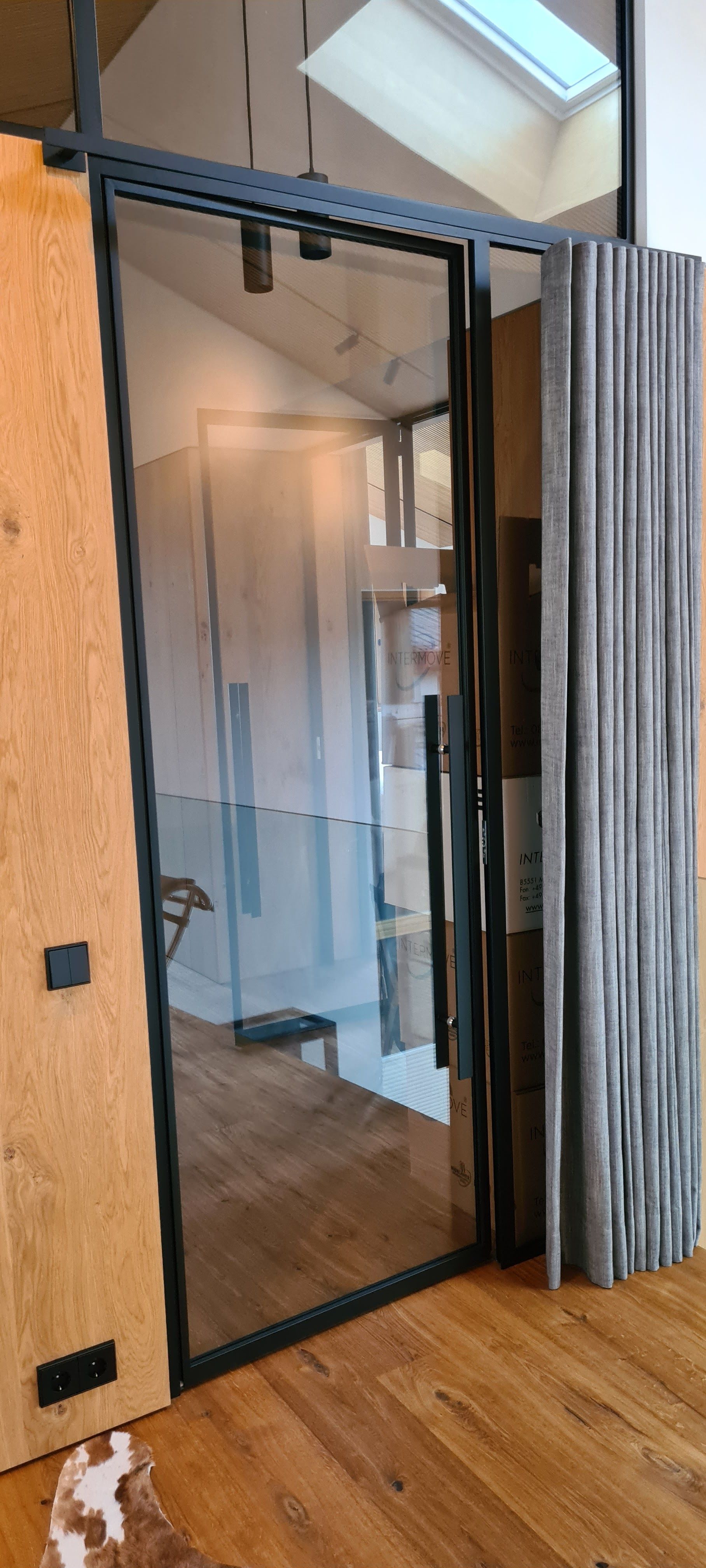 Ein Raum mit einer Glastür und einem Holzboden.