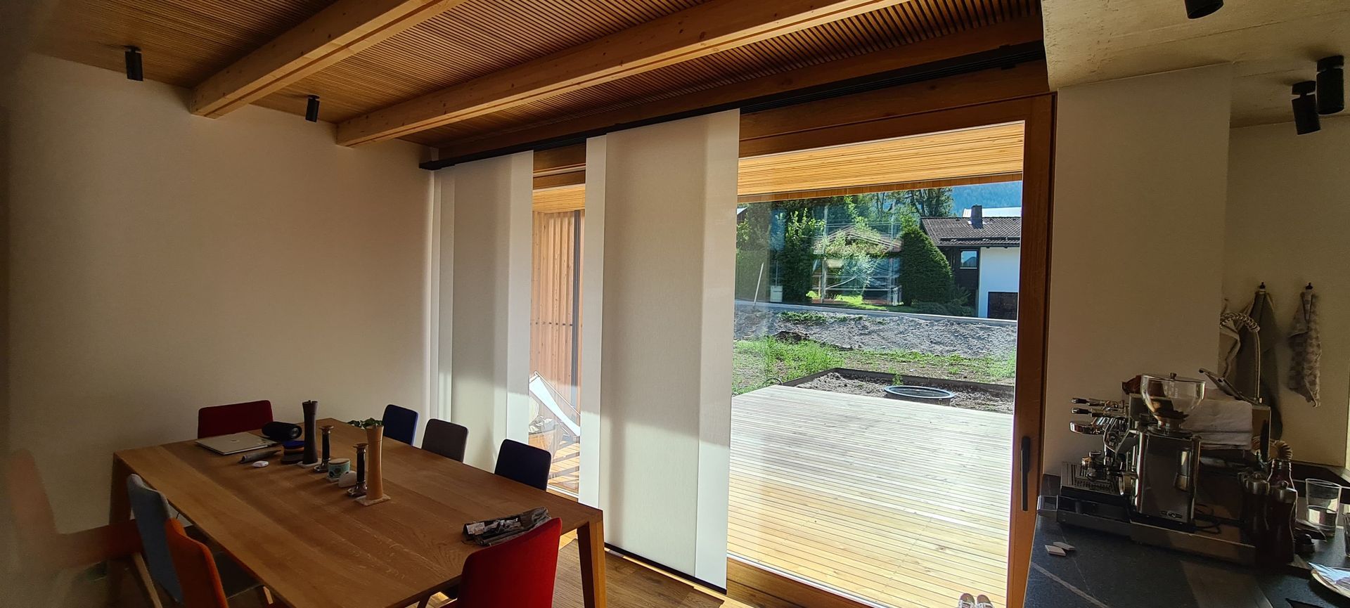 Ein Esszimmer mit einem langen Holztisch und Stühlen und einem großen Fenster.