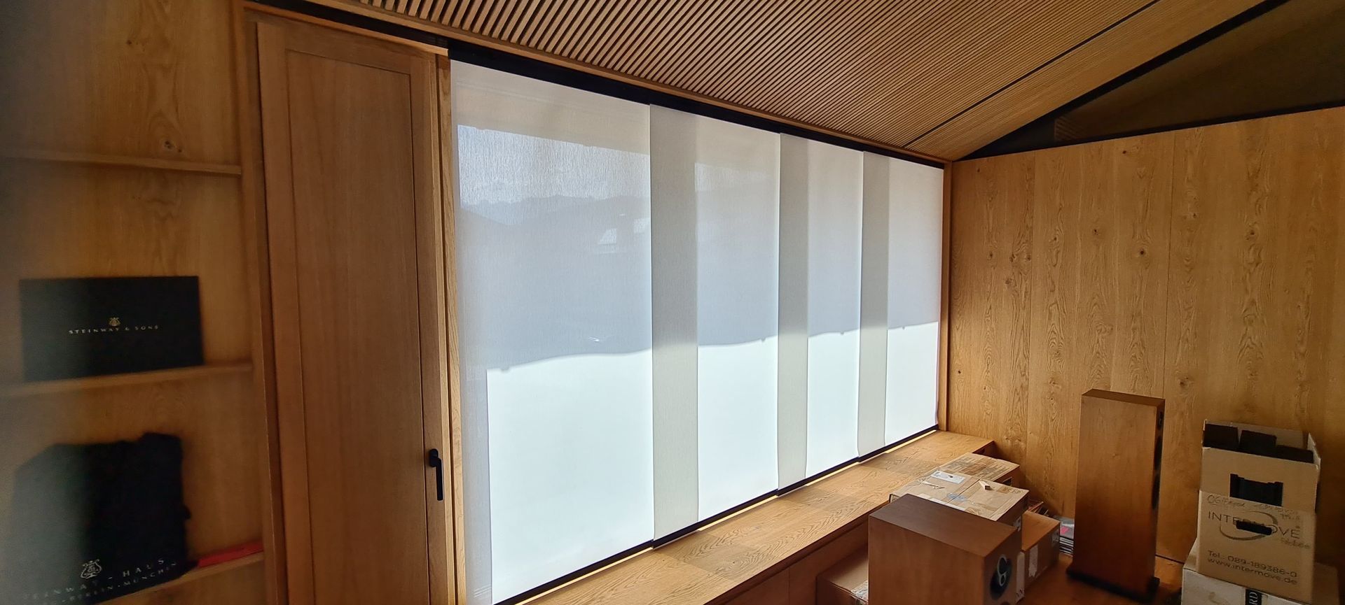 Ein Raum mit einem großen Fenster und einer Holzdecke.