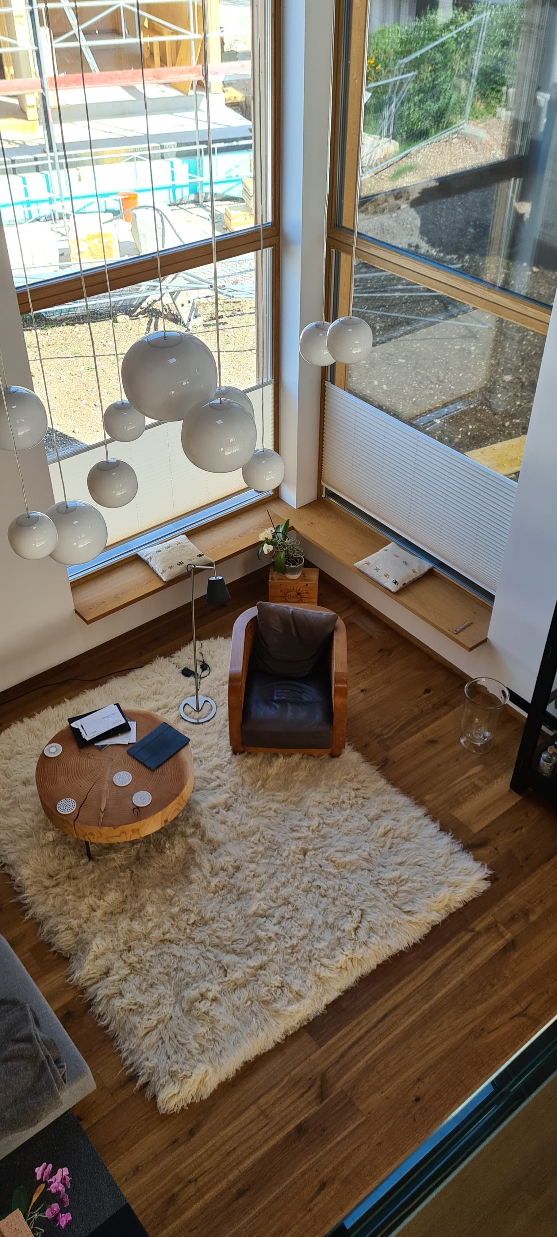 Eine Luftaufnahme eines Wohnzimmers mit Teppich, Stuhl, Tisch und Fenster.