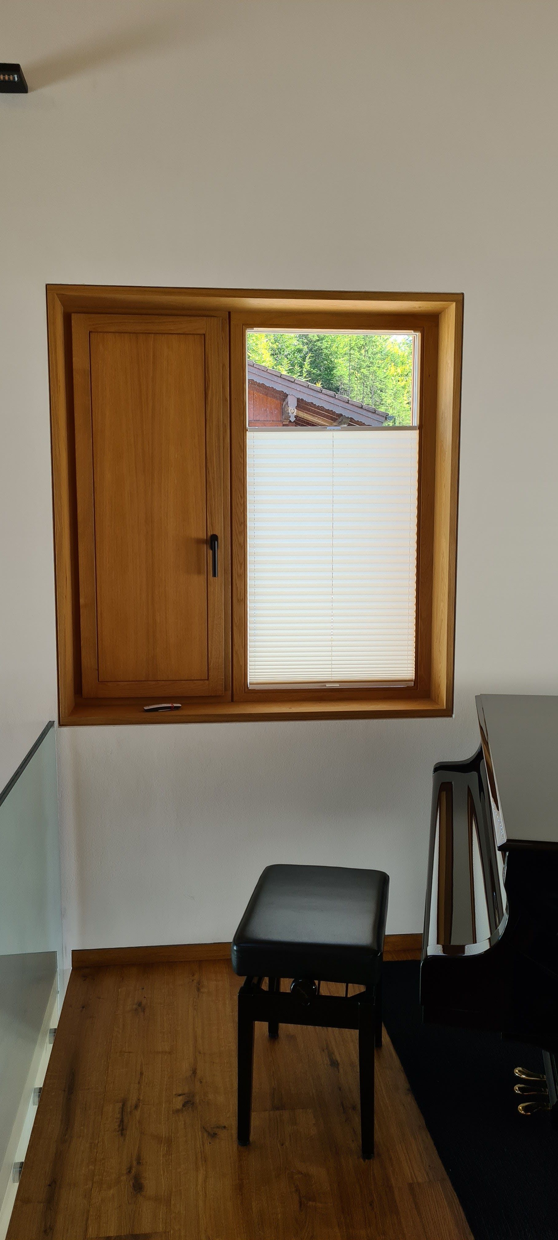 Ein Raum mit einem Klavier und einem Fenster mit einer Bank davor.