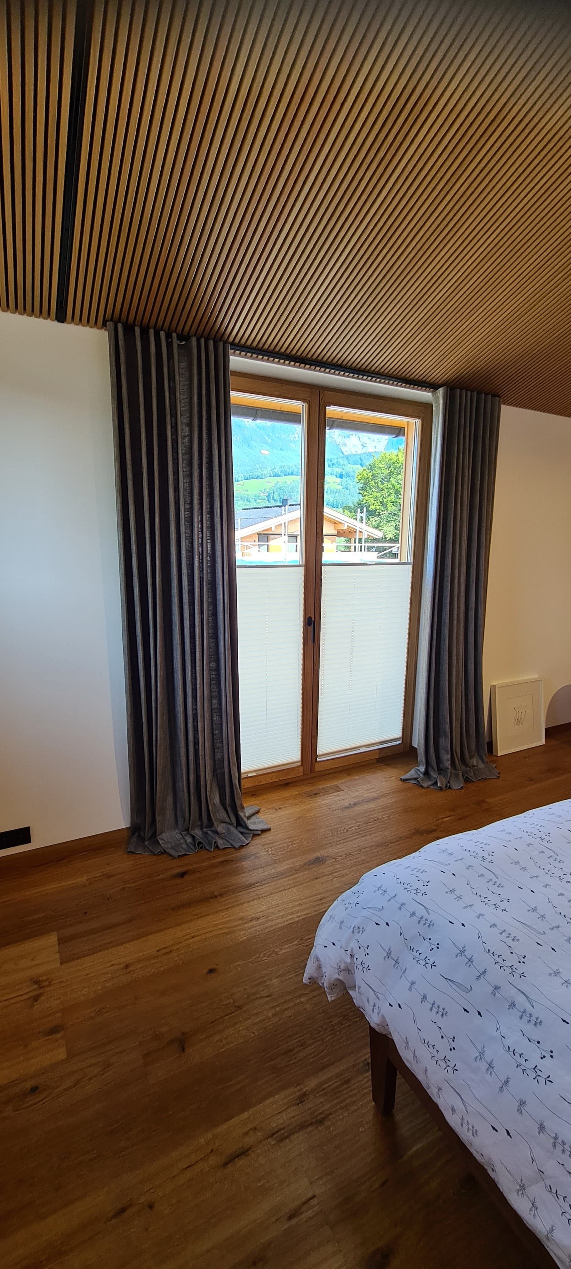 Ein Schlafzimmer mit einem Bett, Glasschiebetüren und Holzböden.