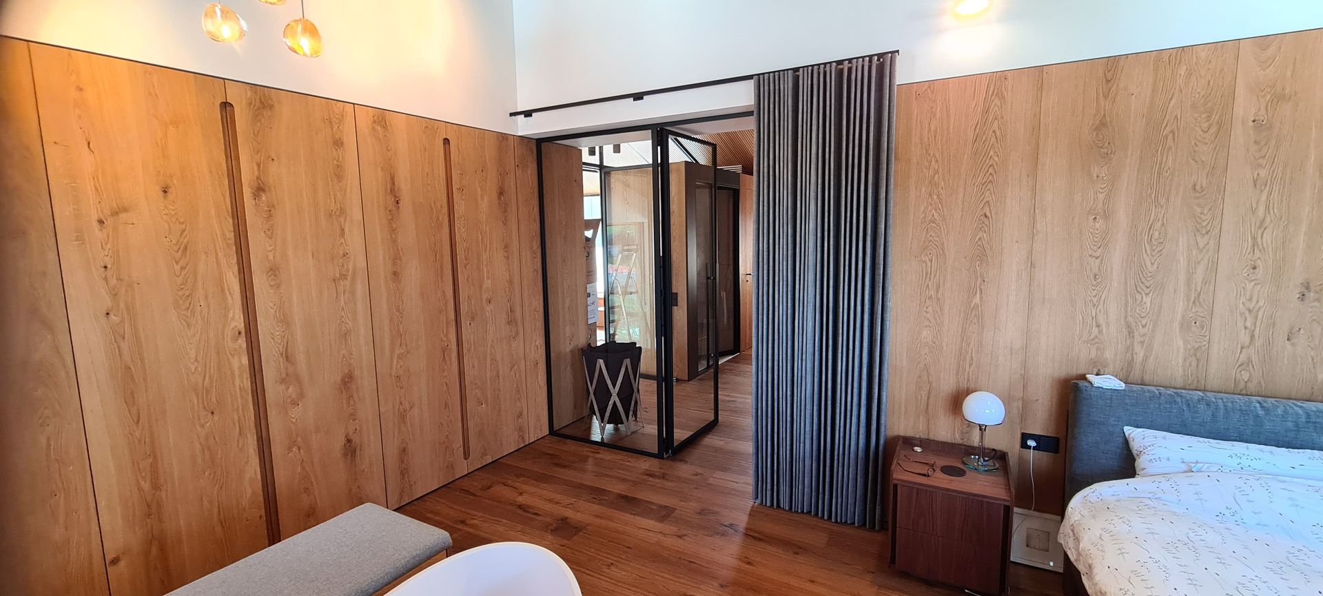 Ein Schlafzimmer mit Bett, Nachttisch, Spiegel und Holzwänden.