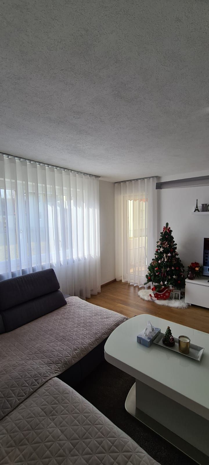 Ein Wohnzimmer mit Sofa, Tisch und Weihnachtsbaum.