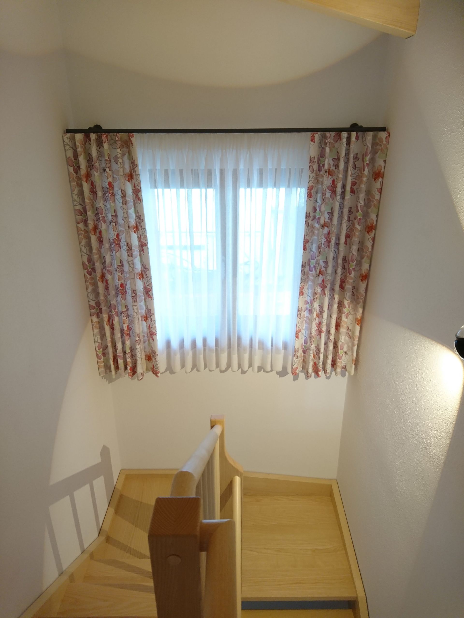 Eine Holztreppe, die zu einem Fenster mit Vorhängen führt
