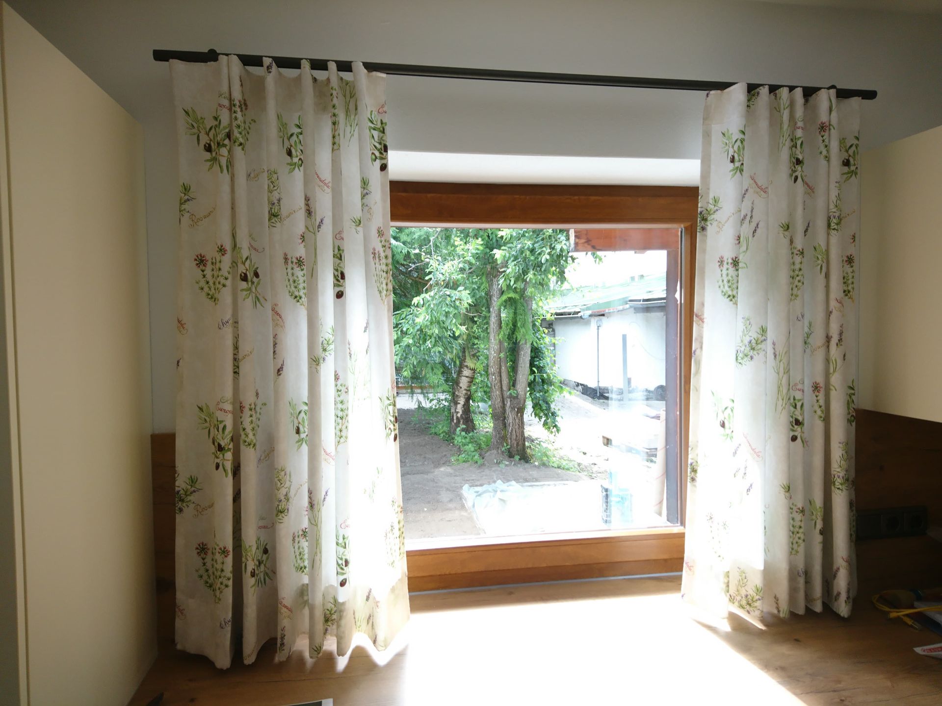 Ein Fenster mit weißen Vorhängen und Blick auf Bäume