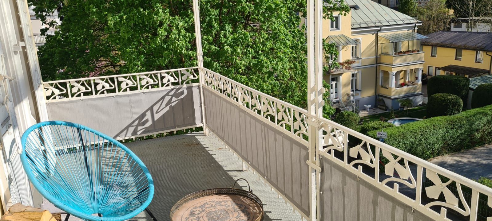 Ein Balkon mit einem blauen Stuhl und einem Tisch.