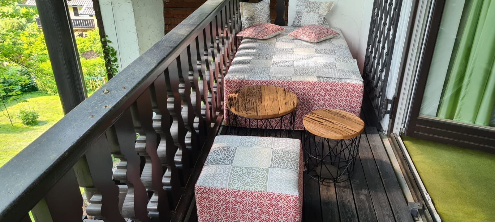 Ein Balkon mit einem Bett und zwei Ottomanen darauf.