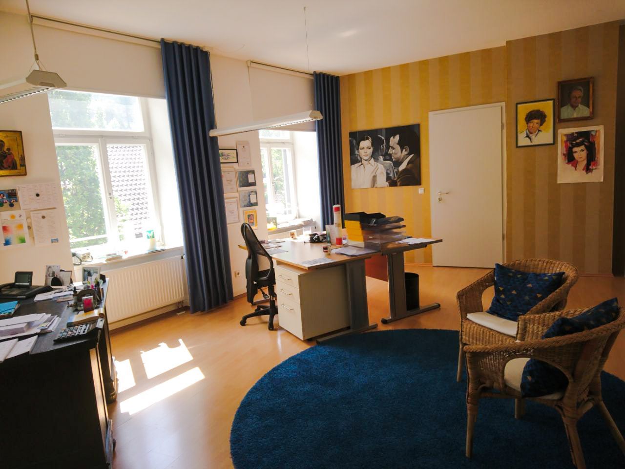 Ein Zimmer mit zwei Stühlen und einem Schreibtisch mit Bildern an der Wand