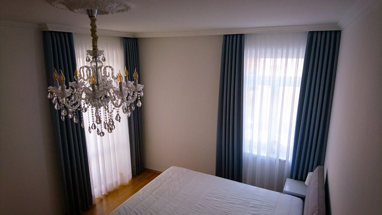 Ein Schlafzimmer mit einem Bett, Vorhängen und einem Kronleuchter.