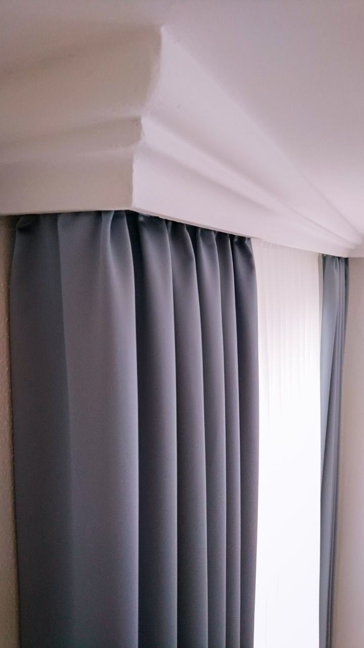 Eine Nahaufnahme eines Paars grauer Vorhänge, die an einem Fenster hängen.