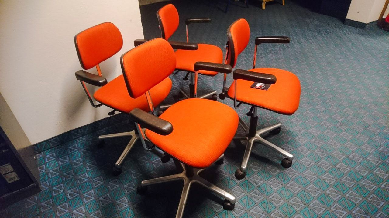 Vier orangefarbene Bürostühle sind übereinander gestapelt